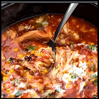 Hearty chicken taco soup topped with shredded cheese, tortilla strips, and fresh cilantro.