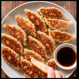 Pan-seared gyoza dumplings with crispy golden-brown bottoms served with dipping sauce.