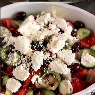 Traditional Greek salad topped with large slabs of feta cheese and dried oregano
